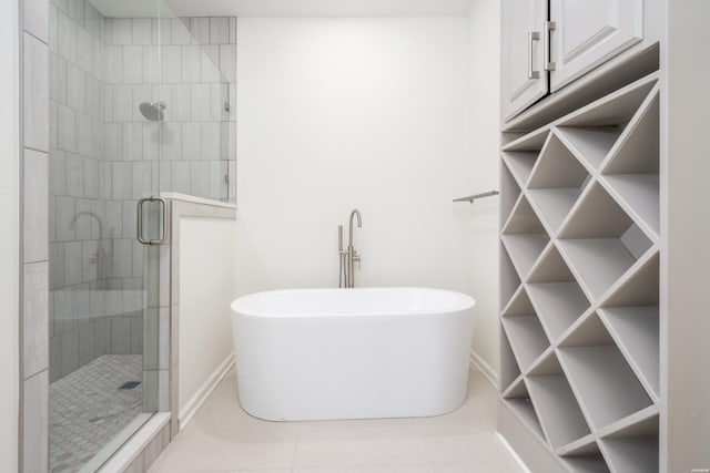 bathroom with a stall shower, baseboards, and a freestanding tub