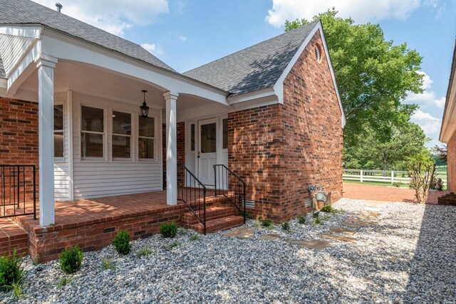 view of front of house featuring brick siding, a shingled roof, and fence