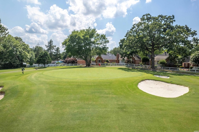 view of home's community featuring view of golf course and fence