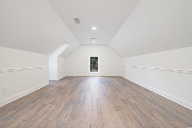 additional living space featuring vaulted ceiling, baseboards, visible vents, and wood finished floors