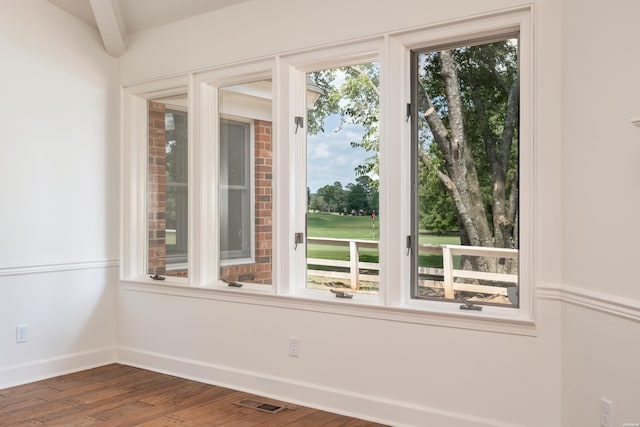 spare room with golf course view, beam ceiling, visible vents, baseboards, and dark wood-style floors