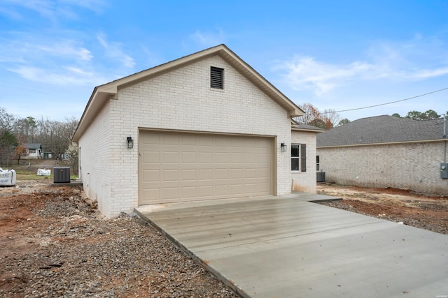 view of side of property with central air condition unit, concrete driveway, and brick siding