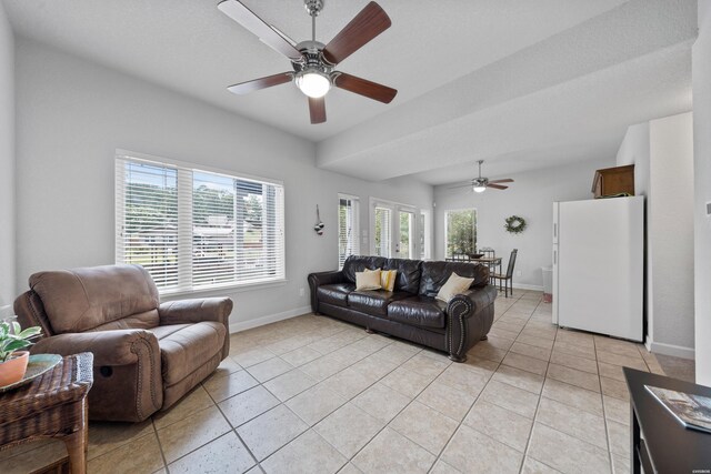 living area featuring a ceiling fan, baseboards, and light tile patterned floors