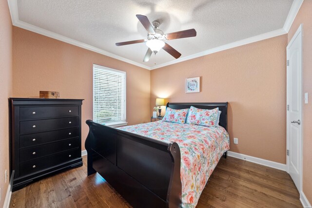 bedroom with a textured ceiling, baseboards, dark wood finished floors, and crown molding