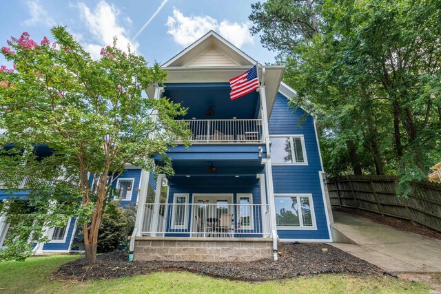 back of house featuring a balcony, fence, and a porch