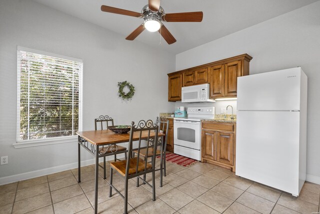 kitchen featuring light stone countertops, white appliances, light tile patterned floors, and brown cabinetry