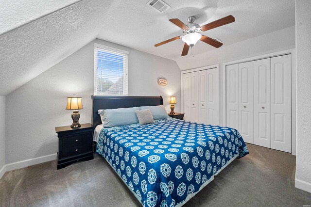 bedroom featuring vaulted ceiling, dark carpet, two closets, and visible vents