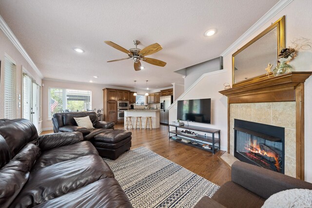 living room featuring a fireplace, recessed lighting, ornamental molding, ceiling fan, and wood finished floors