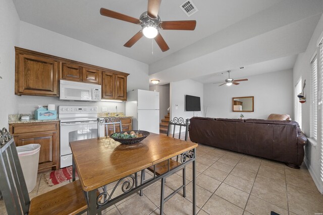 kitchen with white appliances, visible vents, brown cabinets, open floor plan, and light tile patterned flooring