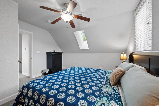 bedroom featuring vaulted ceiling with skylight, carpet floors, visible vents, a ceiling fan, and baseboards