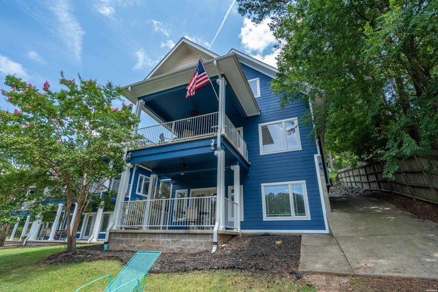 back of house with covered porch, fence, and a balcony