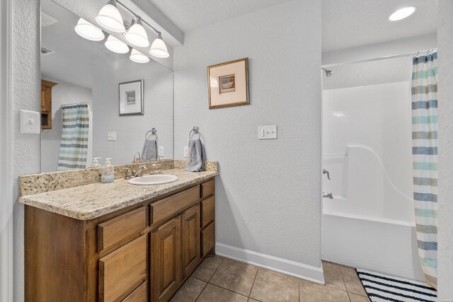 full bath featuring a textured wall, shower / tub combo, vanity, baseboards, and tile patterned floors