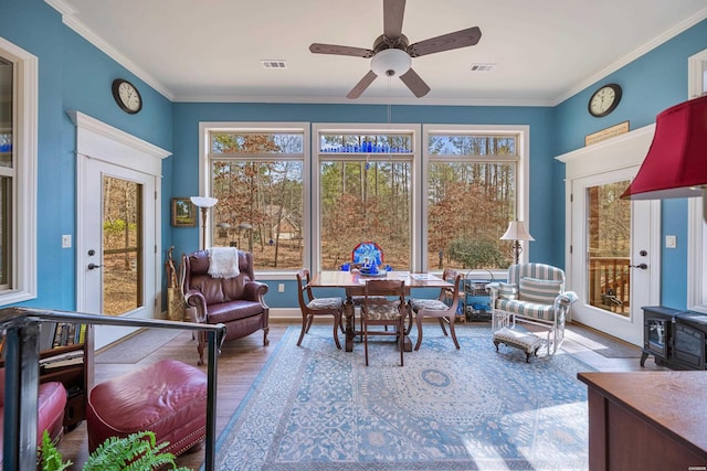 sunroom featuring a wood stove, a ceiling fan, and visible vents