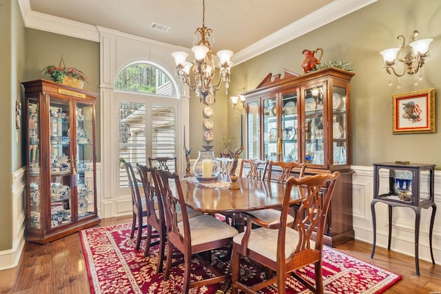 dining area featuring crown molding, wood finished floors, visible vents, and a chandelier