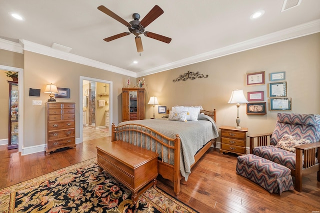 bedroom with hardwood / wood-style flooring, crown molding, visible vents, and baseboards