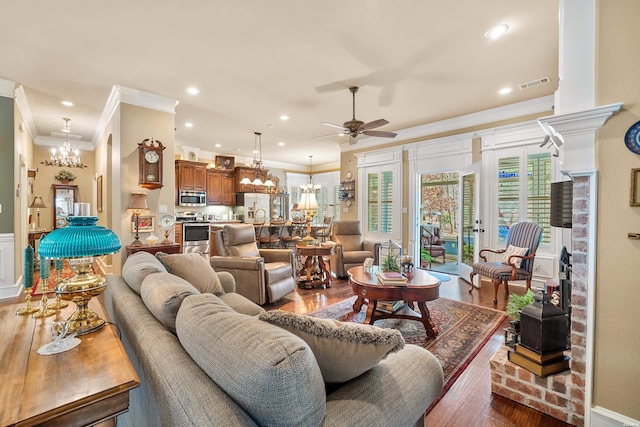 living room featuring visible vents, recessed lighting, dark wood-style flooring, crown molding, and ceiling fan with notable chandelier