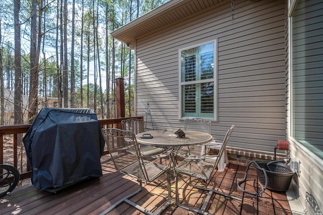 wooden terrace with outdoor dining space and grilling area