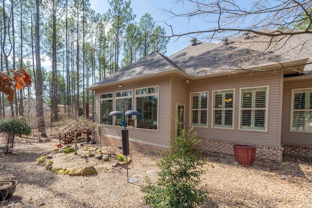 back of property with a sunroom and roof with shingles