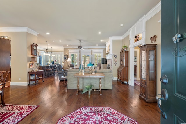 living room with baseboards, decorative columns, ornamental molding, ceiling fan, and dark wood-type flooring