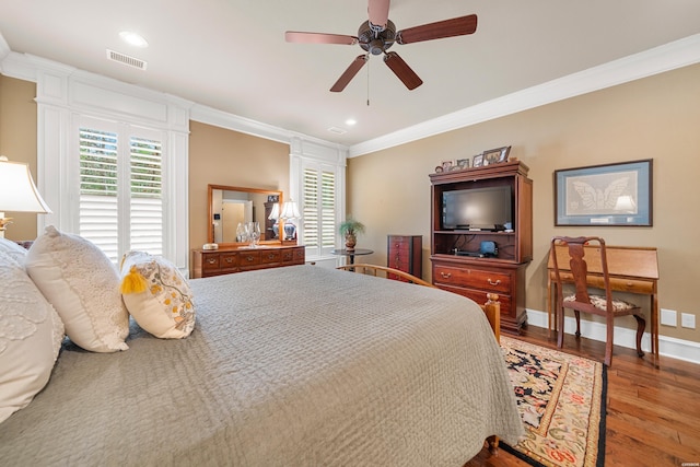 bedroom with visible vents, wood finished floors, baseboards, and ornamental molding