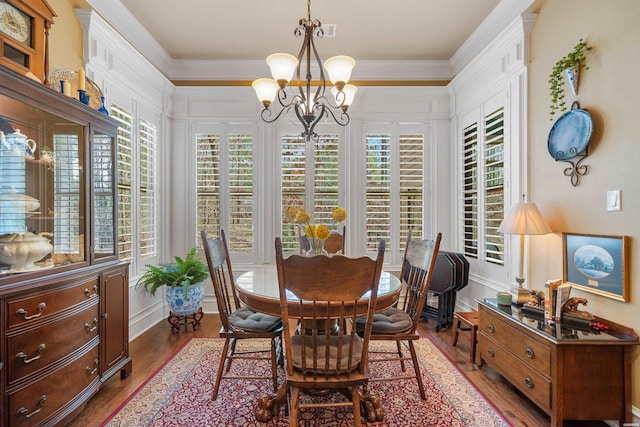 dining space featuring dark wood finished floors, a notable chandelier, visible vents, and ornamental molding