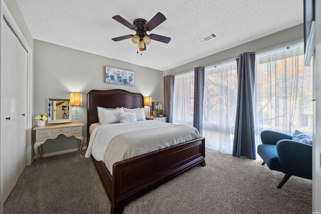 bedroom featuring a textured ceiling, carpet floors, visible vents, and a ceiling fan