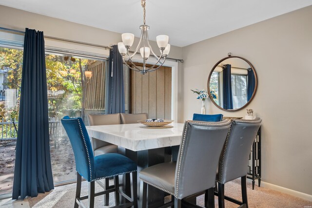 dining space featuring a chandelier, baseboards, and light colored carpet