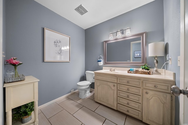 bathroom featuring visible vents, vanity, toilet, and baseboards