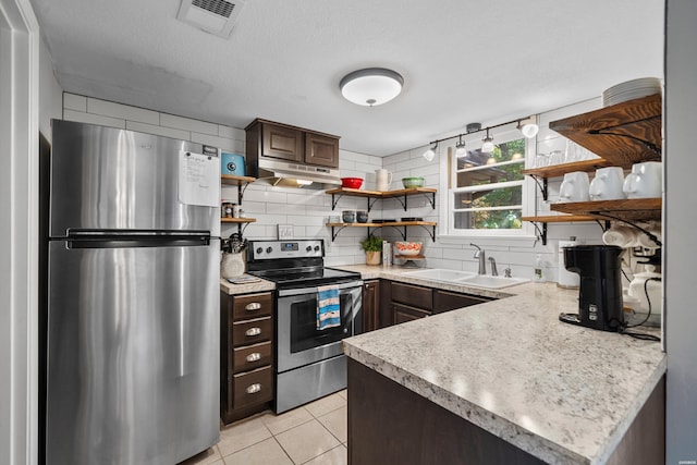 kitchen with light countertops, appliances with stainless steel finishes, a sink, and dark brown cabinetry