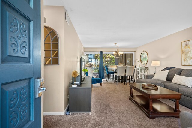 carpeted living area featuring baseboards, visible vents, and a chandelier