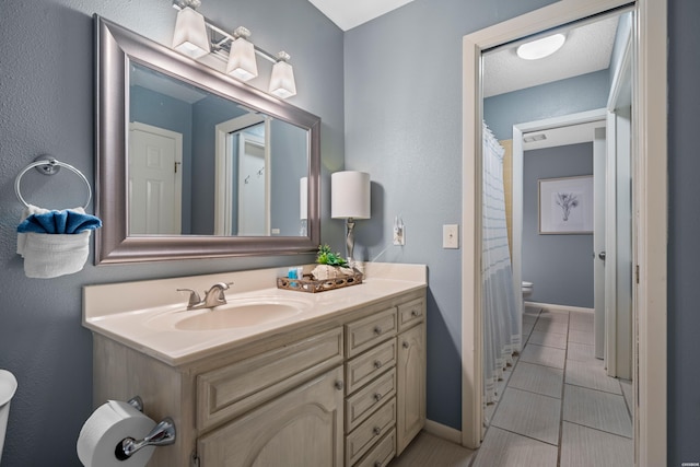 full bathroom with baseboards, vanity, and toilet