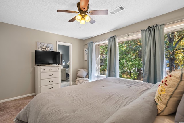 bedroom featuring carpet, visible vents, ensuite bathroom, a textured ceiling, and baseboards