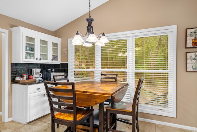 dining room with baseboards, vaulted ceiling, a notable chandelier, and light tile patterned flooring