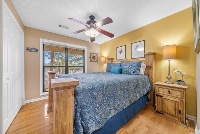 bedroom with a textured ceiling, baseboards, visible vents, and light wood-style floors