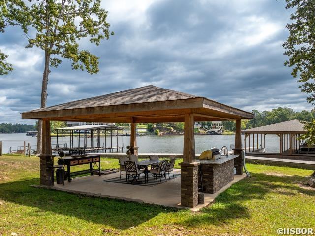 view of property's community with a water view, a lawn, a gazebo, and a patio