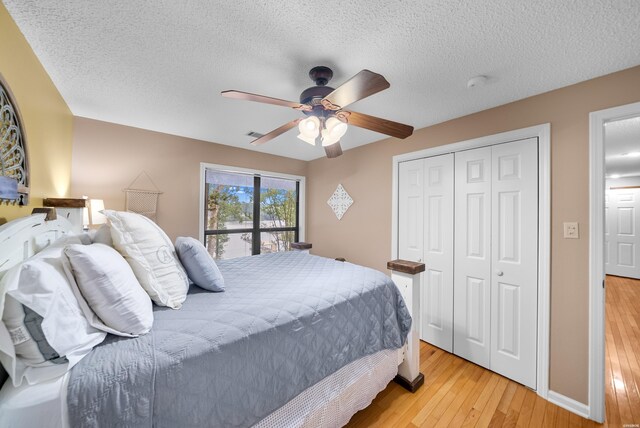 bedroom featuring light wood-style floors, a textured ceiling, a ceiling fan, and a closet