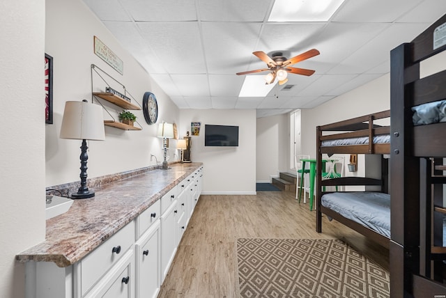 bedroom featuring a paneled ceiling, baseboards, visible vents, and light wood finished floors