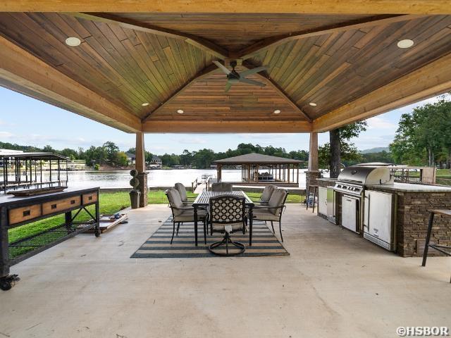 view of patio featuring ceiling fan, area for grilling, a grill, a water view, and a gazebo