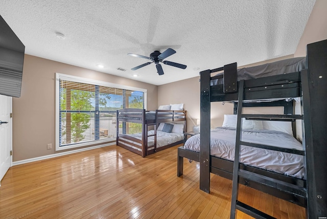 bedroom with a textured ceiling, ceiling fan, wood finished floors, and baseboards