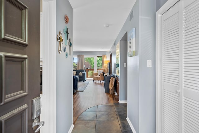 corridor with dark tile patterned flooring, visible vents, and baseboards