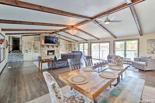 dining room with vaulted ceiling with beams, dark wood finished floors, a fireplace, and a ceiling fan