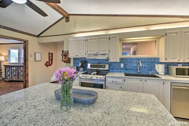 kitchen with white cabinets, under cabinet range hood, stainless steel appliances, and a sink