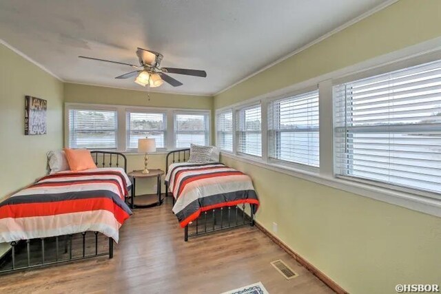 bedroom featuring light wood finished floors, visible vents, ornamental molding, ceiling fan, and baseboards