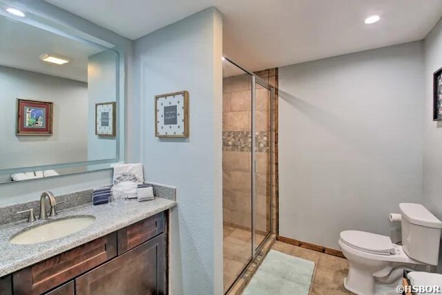 bathroom featuring toilet, vanity, a shower stall, tile patterned flooring, and baseboards