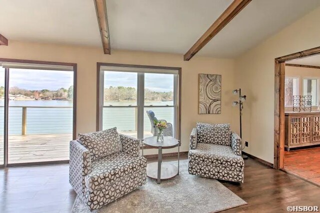 sitting room with a water view, vaulted ceiling with beams, baseboards, and dark wood-style flooring