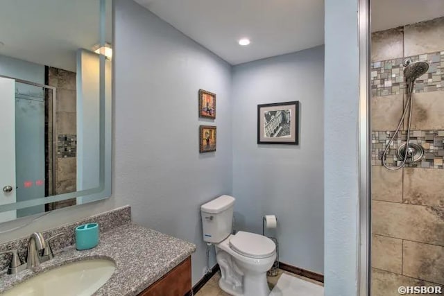 bathroom featuring baseboards, toilet, a shower stall, and vanity