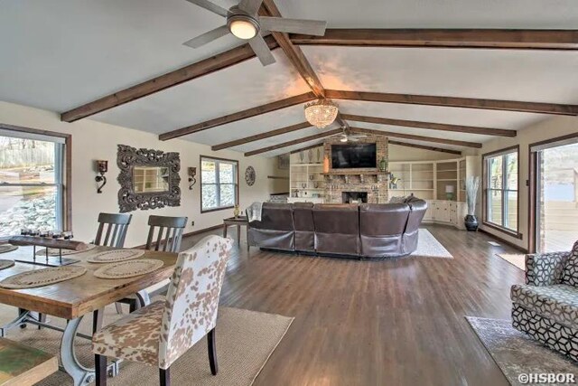 dining room featuring a large fireplace, baseboards, a ceiling fan, lofted ceiling with beams, and wood finished floors