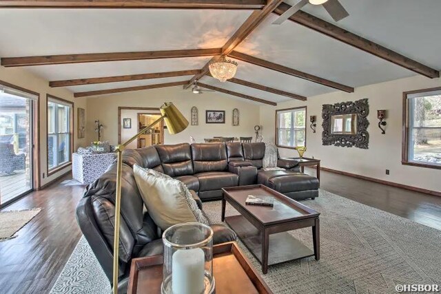 living area featuring lofted ceiling with beams, dark wood-style flooring, a ceiling fan, and a healthy amount of sunlight