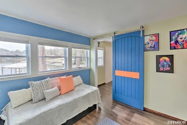 sitting room with a barn door, wood finished floors, and baseboards