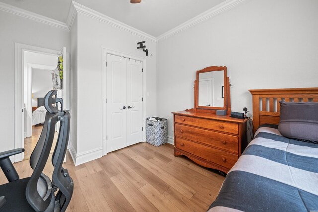 bedroom with crown molding, baseboards, and light wood-style flooring